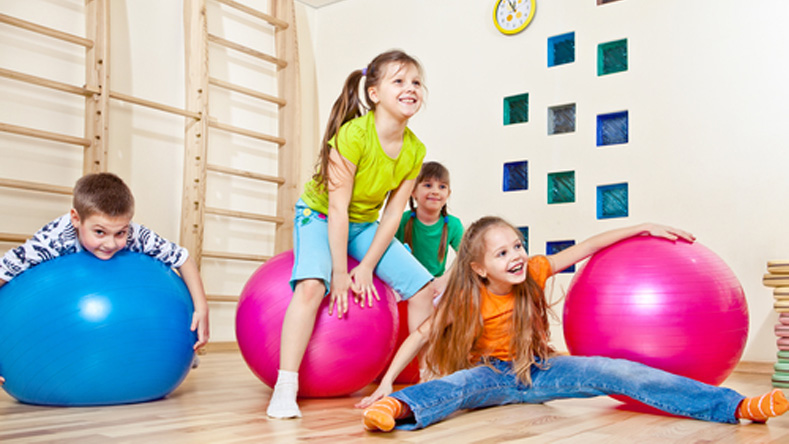 Děti si v tělocvičně hrají a skákají na balonech